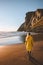 Woman traveling solo walking on beach looking at sunset ocean view