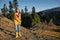 Woman traveling to the mountains in the fall on a nature hike smile and happiness in a yellow cape with red hair full