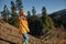 Woman traveling to the mountains in the fall on a nature hike smile and happiness in a yellow cape with red hair full