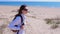 Woman traveller with backpack is looking around in sea sand beach on vacation.