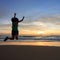 Woman traveller happy jumping on the beach with sunrise