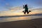 Woman traveller happy jumping on the beach with sunrise