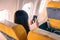 Woman traveller passenger sitting at airplane seat using smartphone onboard