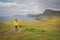 Woman traveller standing with her hends raised on the beautiful scenic coast