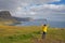 Woman traveller standing with her hends raised on the beautiful scenic coast