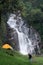 woman traveller walk togather Tent and camping with Mae Tia waterfall and mountain background at inthanon national park in Chiang