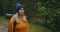 A woman travels on foot in a sweater and hat along a forest road with a backpack and examines the trees and nature