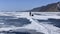 A woman travels on skates on the ice of frozen Lake Baikal. Blue transparent ice