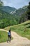 Woman trekking on a winding dirt lane, road ascending a mountain