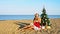 Woman on a tropical beach with a Christmas tree