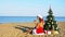 Woman on a tropical beach with a Christmas tree