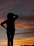 Woman in trousers with hat silhouette looking at sunset, sunrise. Background with copyspace.