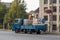 A woman from a truck watering flowers in the street in hanging flowerpots.