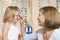 Woman trying glasses on young girl at optometrists