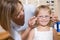 Woman trying glasses on young girl at optometrists