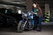 Woman trying to sit on motorcycle, standing in dark parking