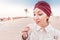 Woman with turban tasting arabian coffee while having tour and excursion in midlle eastern desert