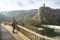 Woman turist poses on the old wooden bridge opposite impressive cliff village Castellfullit de la Roca