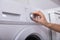 Woman Turning Button Of Washing Machine