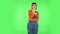 Woman with TV remote in her hand, switching on TV. Green screen