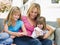 Woman and two young girls sitting on patio reading