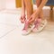 Woman tying her shoes. Pink shiny color girl shoes