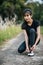 Woman tying shoelaces on concrete road to exercise in fresh atmosphere.