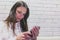 Woman is typing a message on mobile phone sitting and waiting somebody in cafe.