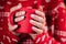 Woman in ugly sweater holding cozy red mug on Christmas tree background. Girl with hot drink - tea, coffee or cocoa