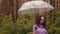 A woman with an umbrella in her hand in the rain. A girl in a purple shirt under an umbrella in the woods. A woman with