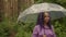 A woman with an umbrella in her hand in the rain. A girl in a purple shirt under an umbrella in the woods. A woman with