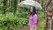 A woman with an umbrella in her hand in the rain. A girl in a purple shirt under an umbrella in the woods. A woman with