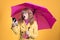 Woman with umbrella looking at mobile phone with surprise