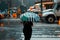 A woman with an umbrella in New York on a rainy stormy day, waiting to cross the road