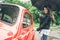 Woman with umbrella sits in red retro car