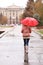 Woman with umbrella taking autumn walk in city