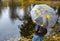 Woman under umbrella stands on the shore of an autumn lake