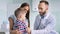 Woman unfastening shirt to little boy for examination chest by doctor using stethoscope