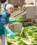 Woman in uniform sorts and washes leeks at vegetable processing factory