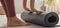 Woman unrolling yoga mat at home, closeup. Horizontal banner design