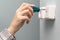 a woman unscrews with a screwdriver repairing a television wall socket