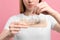 Woman untangling her lost hair from comb on pink background, closeup. Alopecia problem