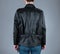 A woman in unzipped black biker leather jacket. Back view.