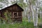 Woman urban explorer smiles through a broken window in an old log cabin in Miners Delight Wyoming