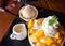 Woman use spoon take shaved ice dessert, served with mango sliced.  Served with vanilla ice cream and whipped cream