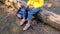 A woman uses a laptop sitting on a log in the woods. Remote work or study. A girl in a yellow jacket and jeans prints