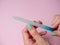 A woman uses a nail file to put her nails in order on a paper pink background. Nail care at home