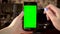 The woman uses the phone. Hand makes swipe left on smartphone with green screen. Chroma key.
