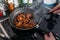 Woman uses a spatula to prepare chicken teriyaki in a pan on the stovetop in the kitchen.