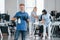 Woman uses vacuum cleaner. Group of workers clean modern office together at daytime